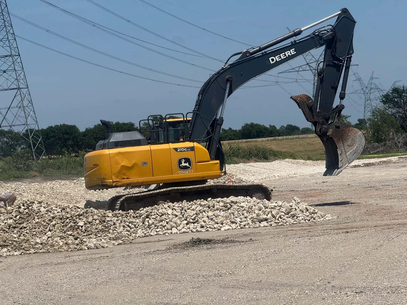 Yellow excavator working a pile of crushed rock on a graded pad